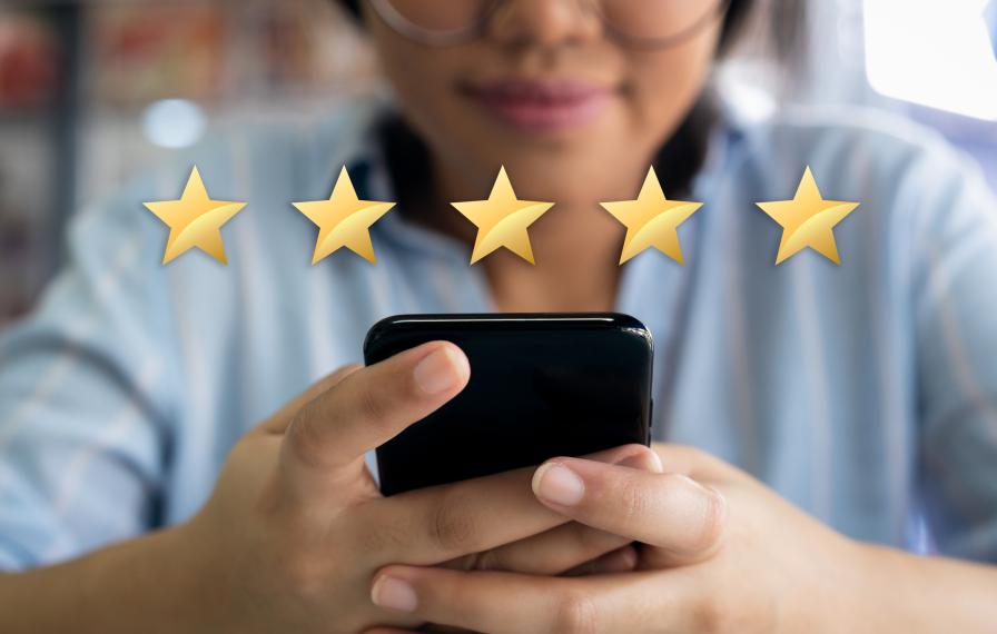 Person looking at their phone with five stars shown above the phone