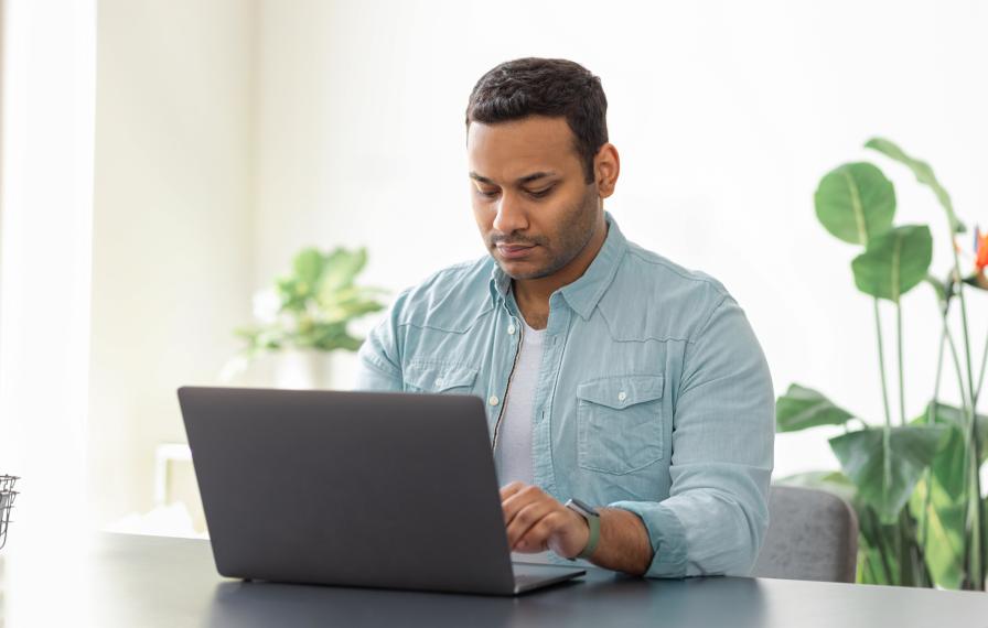 A man in a blue shirt looking at a laptop