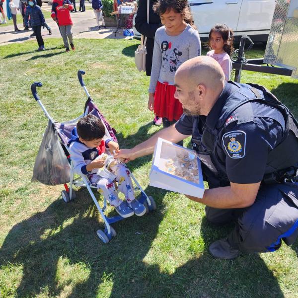 CSU officer handing out a treat to a child in a stroller