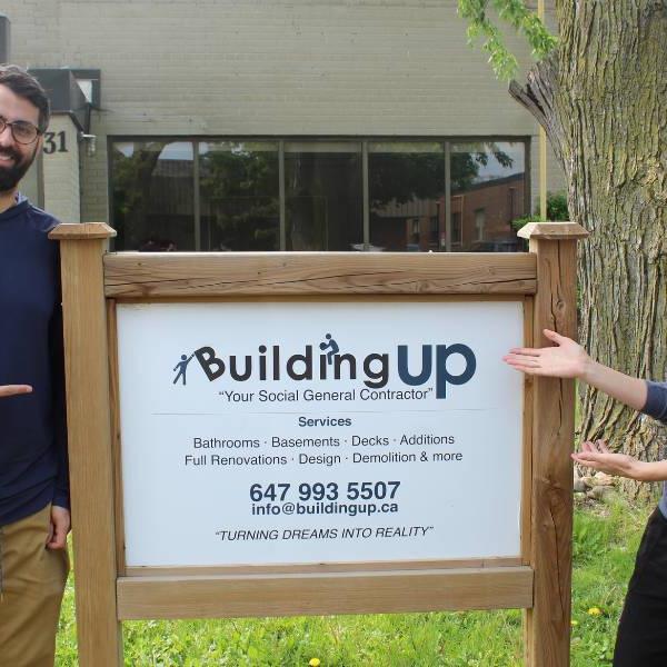 Marc Soberano and Tarah Clark pointing to Building Up's outdoor sign.
