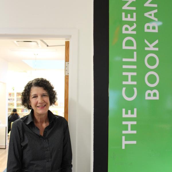 Mary Ladky standing beside a sign that says 'The Children's Book Bank'.