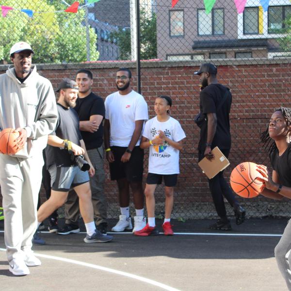 Man passes a basketball to a youth on an outdoor basketball court
