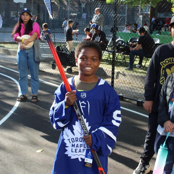 Boy posing with a hockey stick, wearing a Toronto Maple Leafs jersey