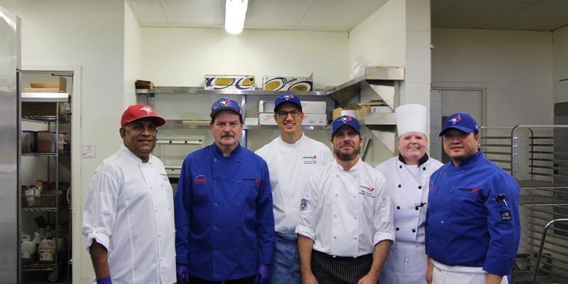 Group photo of chefs and staff in a kitchen
