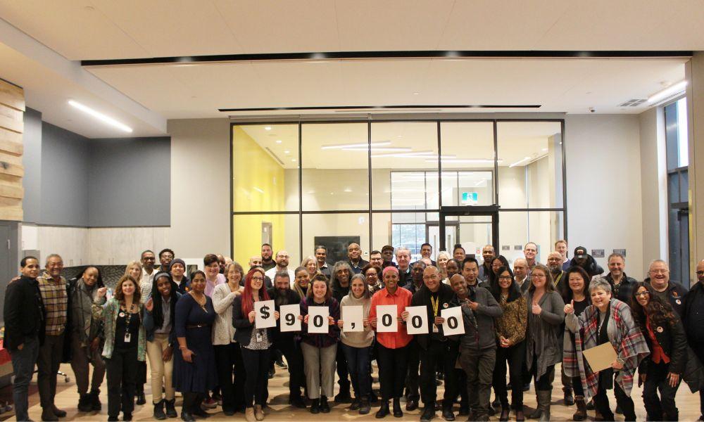 A group of TCHC employee volunteers hold a sign with $90,000 written on it, indicating the amount of money raised for United Way in 2023