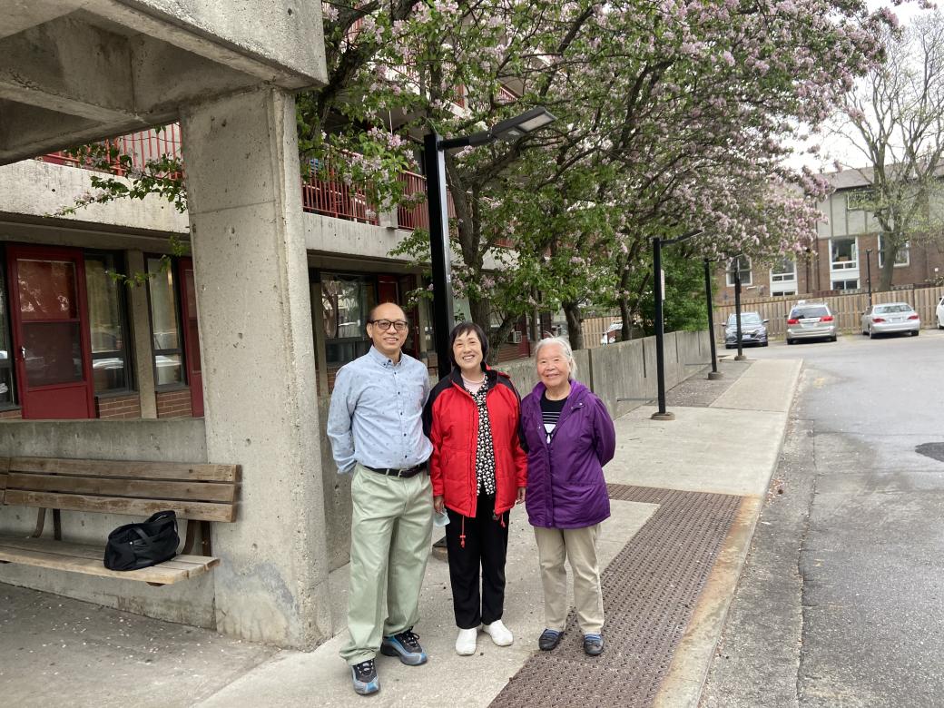 Photo of three tenants standing on the sidewalk outside their building