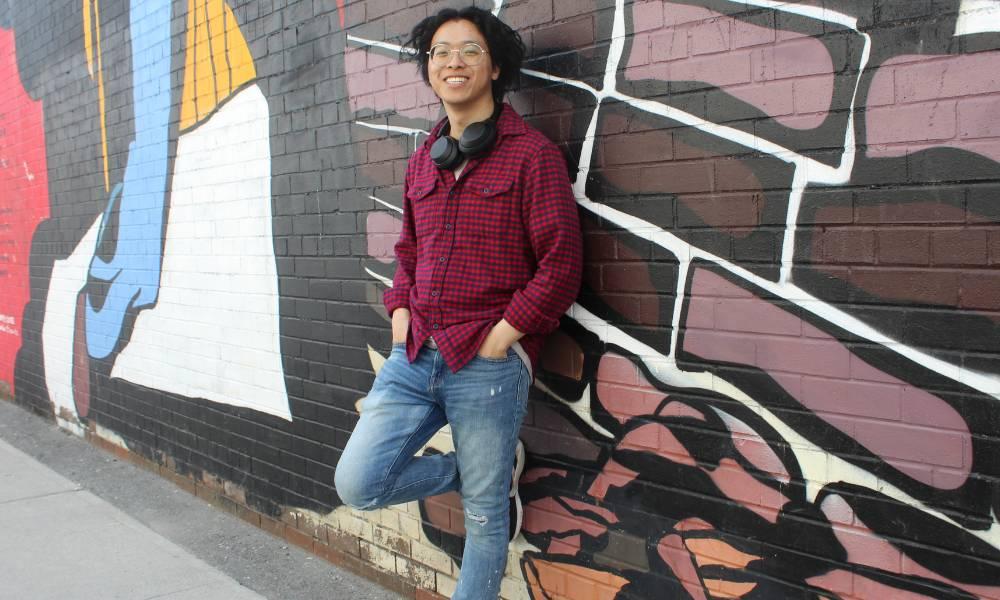 Ken Mao leaning against a graffiti wall.