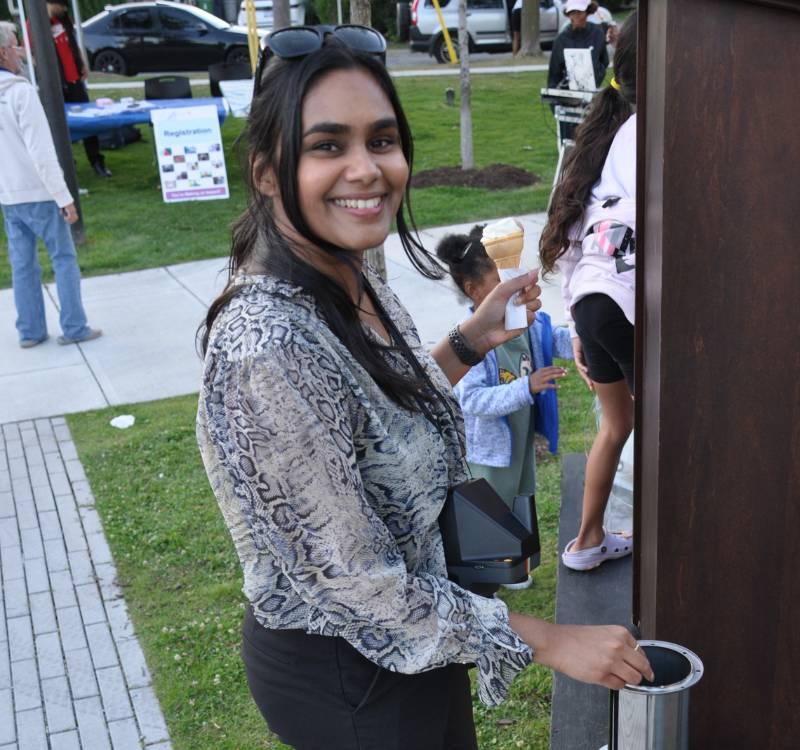 TCHC staff member Rasha Haider stands smiling with an ice cream cone at the Allenbury Gardens community event.