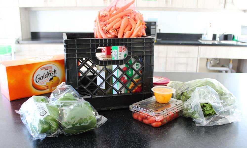 Various groceries, packaged food, and vegetables set out on a kitchen counter.