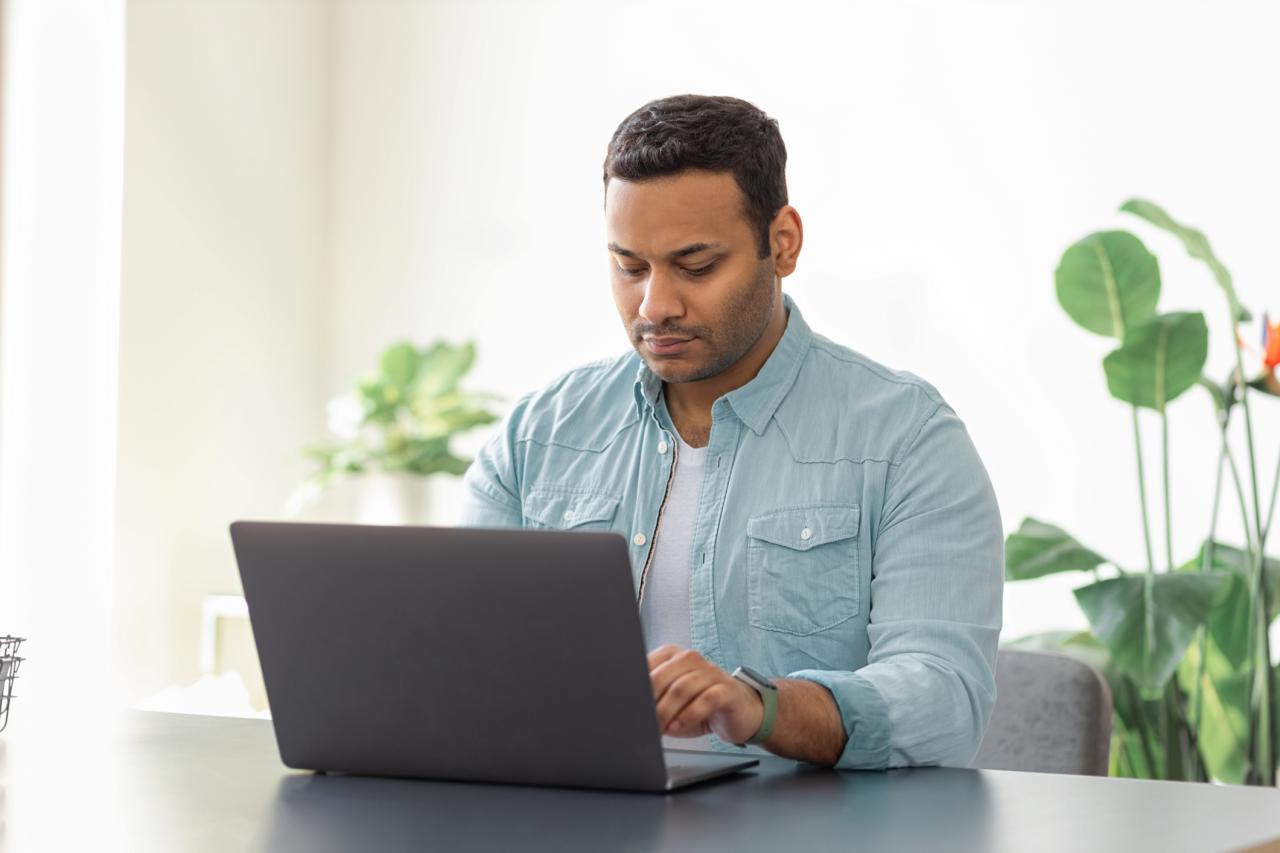 A man in a blue shirt looking at a laptop